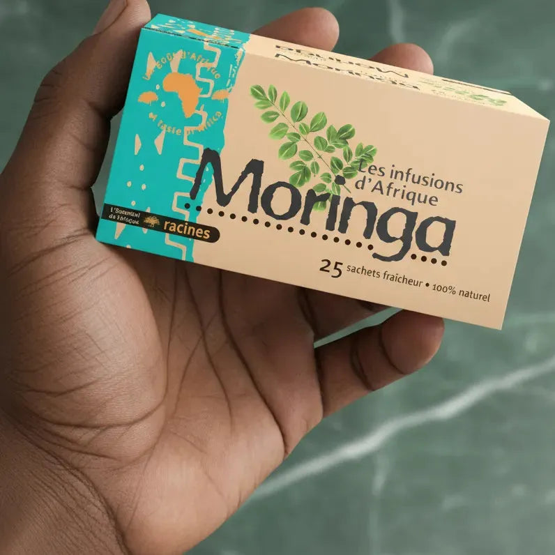 Main tenant une boîte d'infusion Moringa RACINES, 25 sachets fraîcheur, bienfaits naturels et goût doux d’Afrique.
